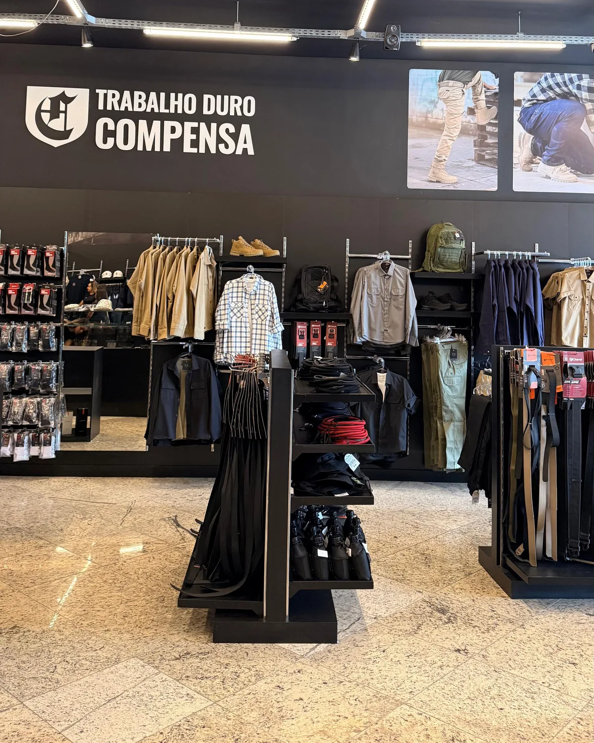 Loja Citerol: painel Trabalho Duro Compensa sobre as araras de camisas e calças