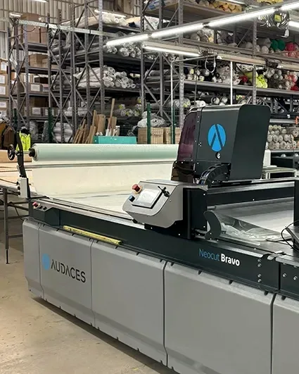 Mesa de corte automatizado da fábrica com o tecido estendido